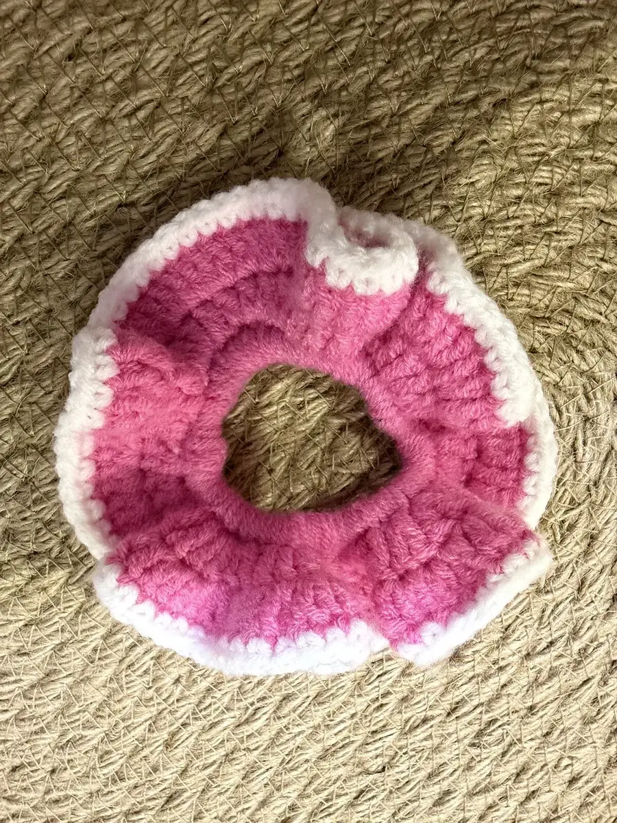 A handmade ruffle scrunchie in bright pink with a white edge.
