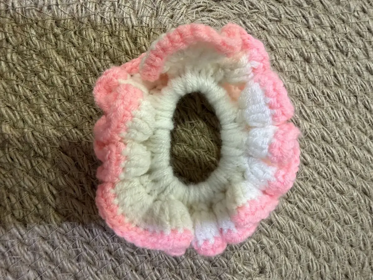 A handmade ruffle scrunchie in white with a pink edge.