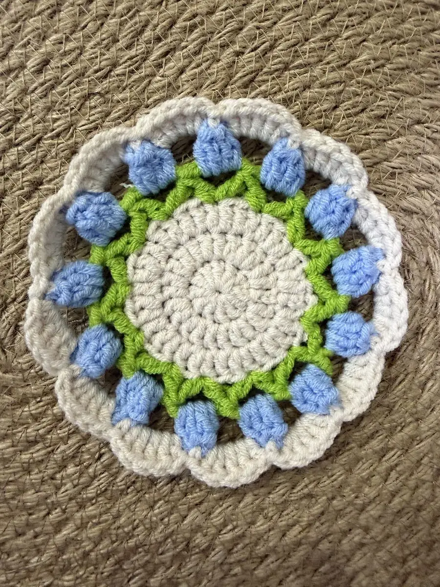 A flower coaster with blue puffs.