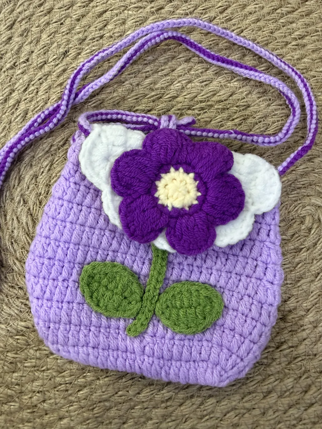A purple crochet bag with a large flower on the front.
