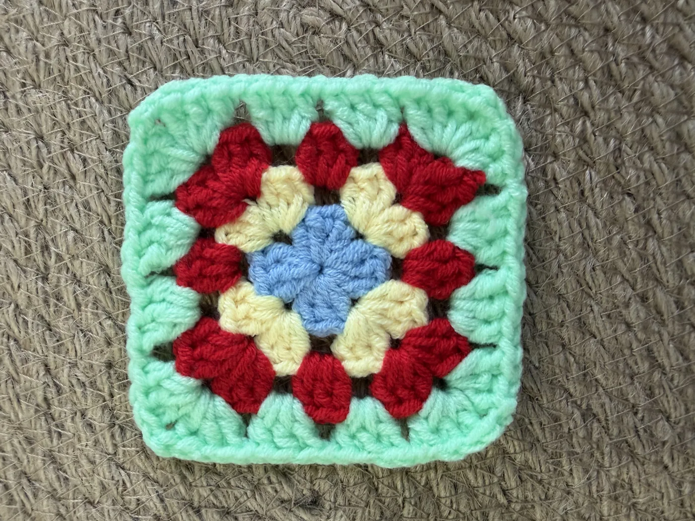 A crochet granny square in red, green and white.